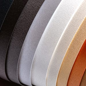 A shimmering sheet of Neenah Pearl paper catching the light with its metallic finish.